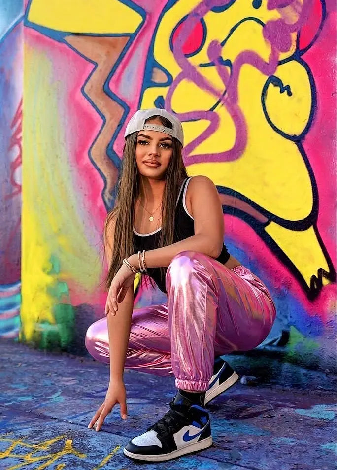 Person posing in front of a colorful graffiti wall
