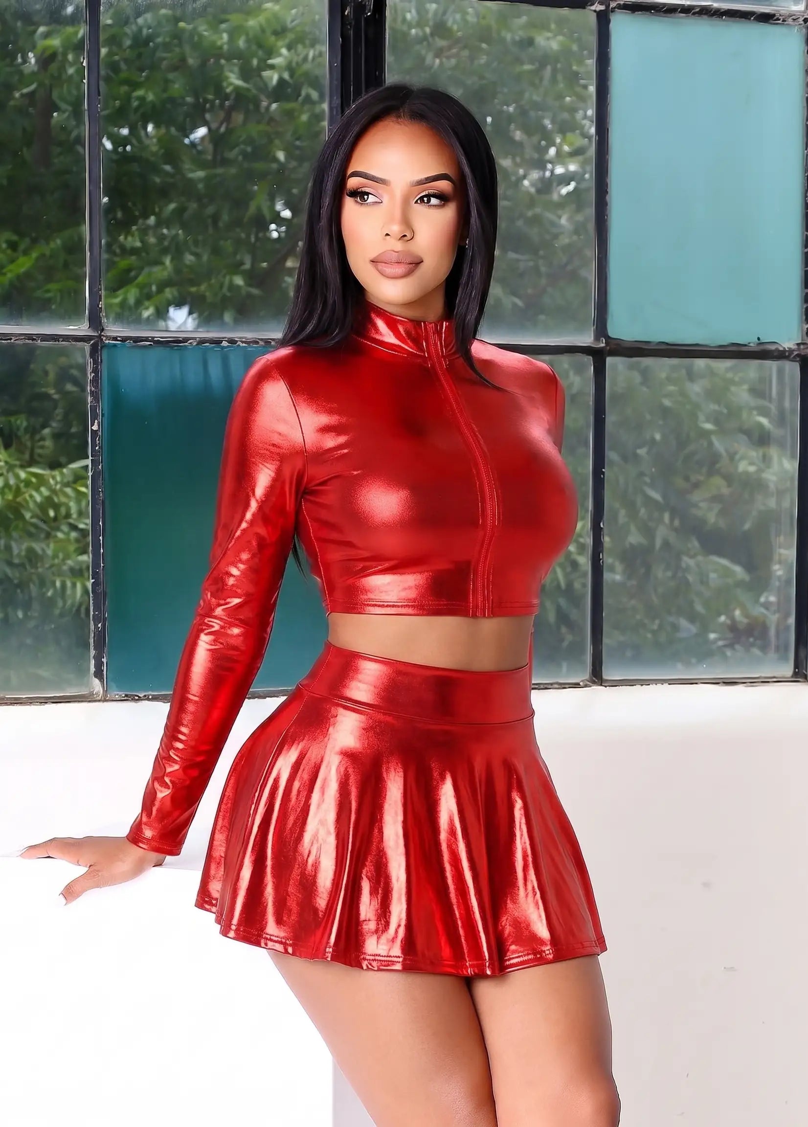 Woman wearing a shiny red outfit in front of a window with greenery.
