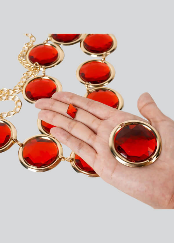 Hand holding a gold necklace with red circular pendants against a light gray background