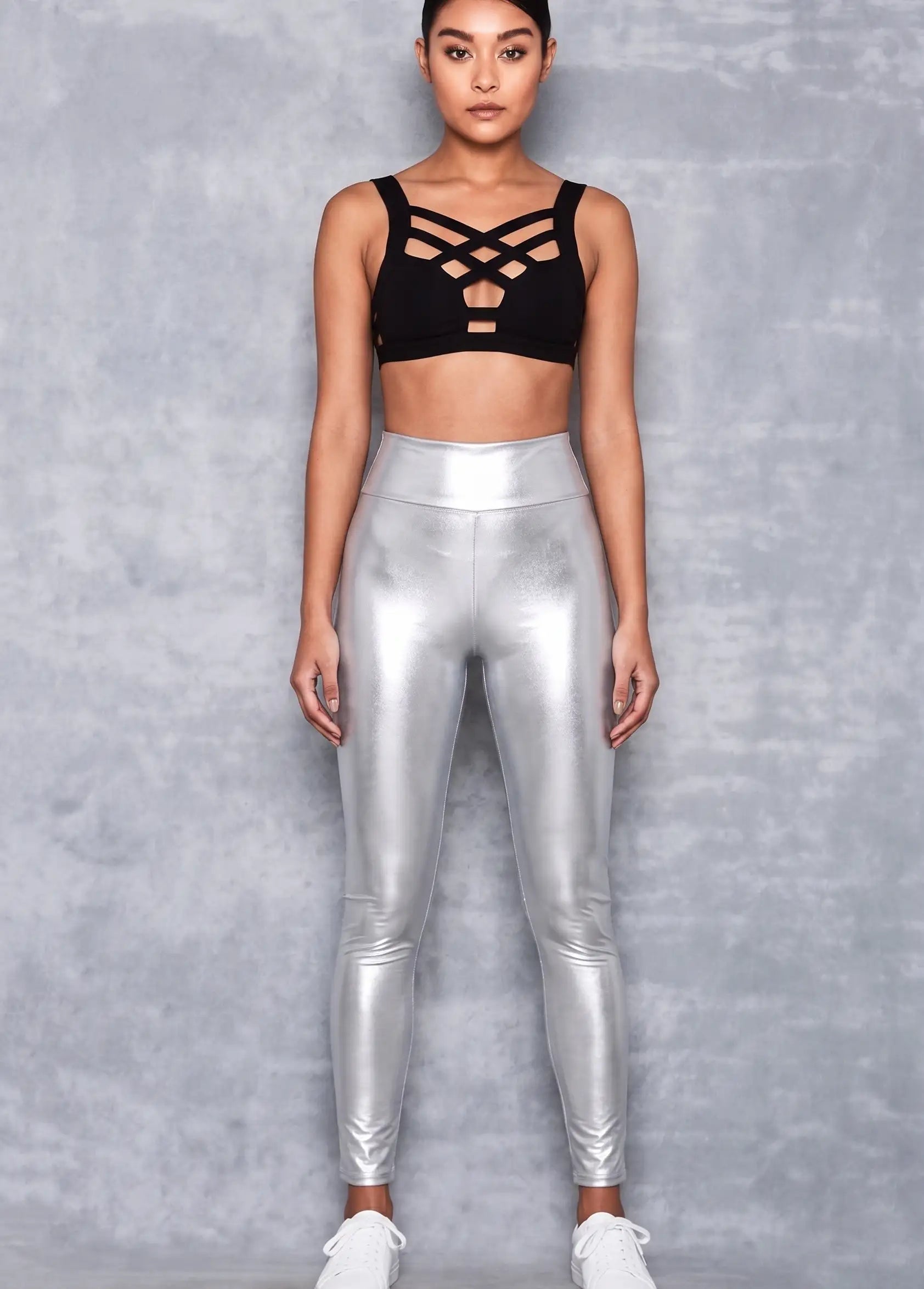 Person wearing a black sports bra and silver leggings against a gray background