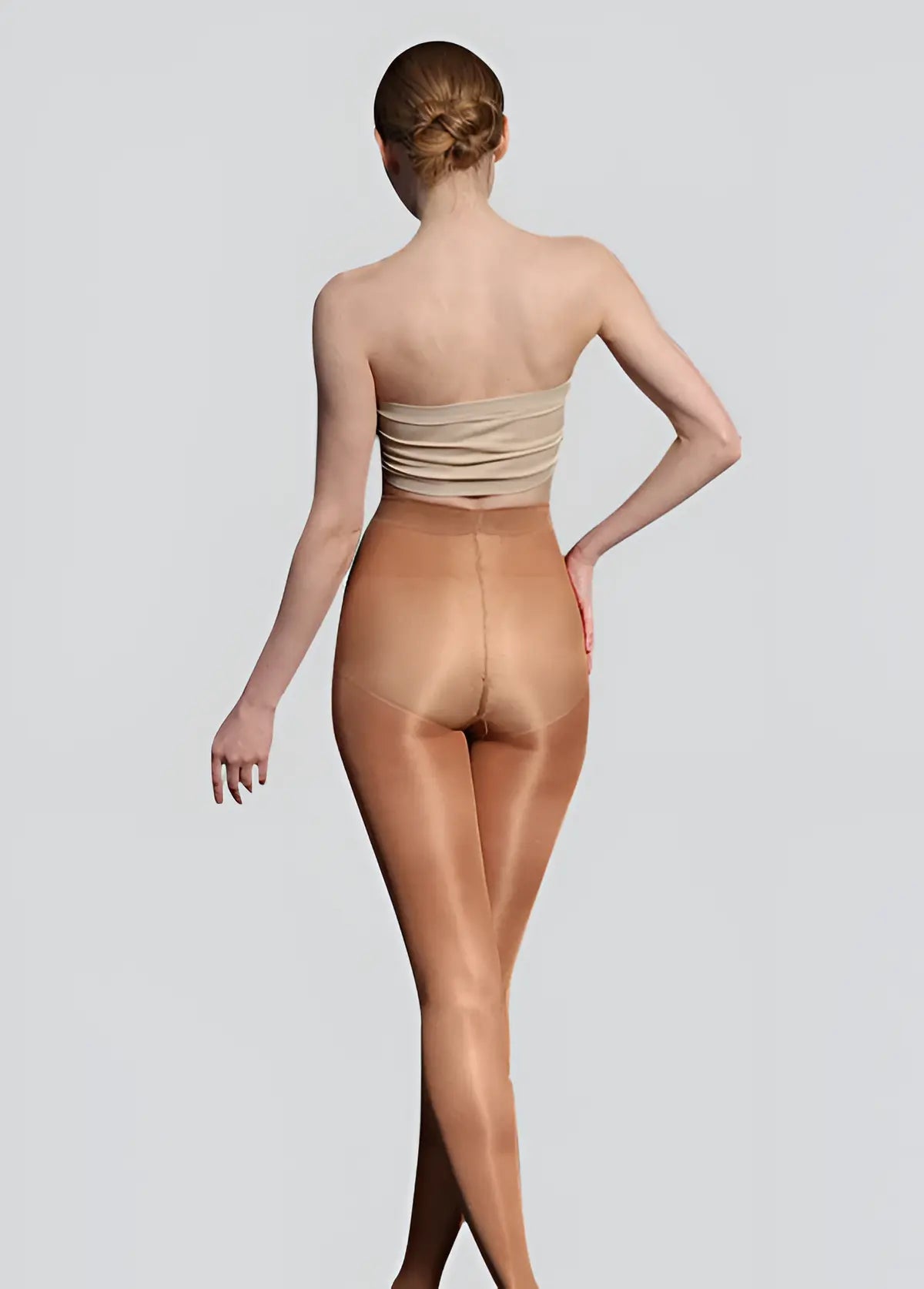 Woman wearing beige strapless top and shapewear on a plain background